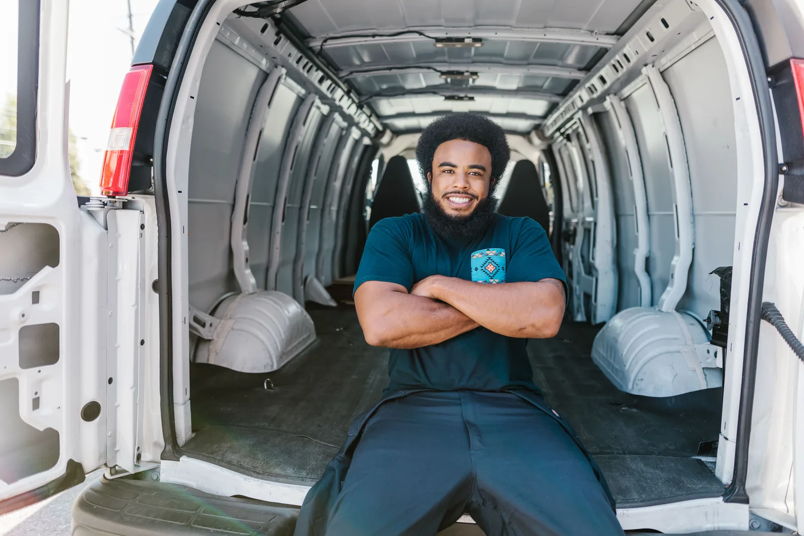 African American man with a beard sitting and smiling inside an empty van, showcasing relaxation and mobility. Do Arizona and Florida snowbird clients pay cash for mobile detailing?